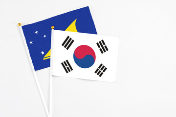 South Korea and Tokelau stick flags on white background. High quality fabric, miniature national flag. Peaceful global concept.White floor for copy space.