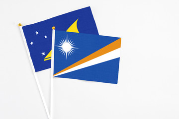 Marshall Islands and Tokelau stick flags on white background. High quality fabric, miniature national flag. Peaceful global concept.White floor for copy space.