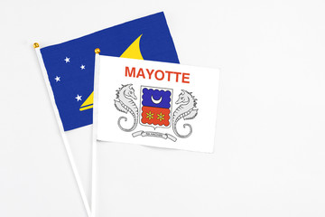 Fototapeta na wymiar Mayotte and Tokelau stick flags on white background. High quality fabric, miniature national flag. Peaceful global concept.White floor for copy space.