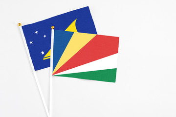 Seychelles and Tokelau stick flags on white background. High quality fabric, miniature national flag. Peaceful global concept.White floor for copy space.