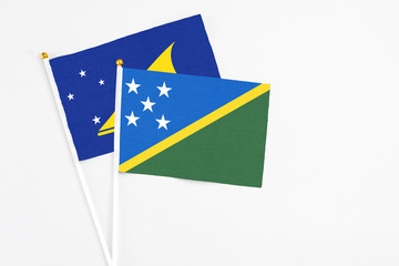Solomon Islands and Tokelau stick flags on white background. High quality fabric, miniature national flag. Peaceful global concept.White floor for copy space.