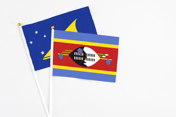 Swaziland and Tokelau stick flags on white background. High quality fabric, miniature national flag. Peaceful global concept.White floor for copy space.