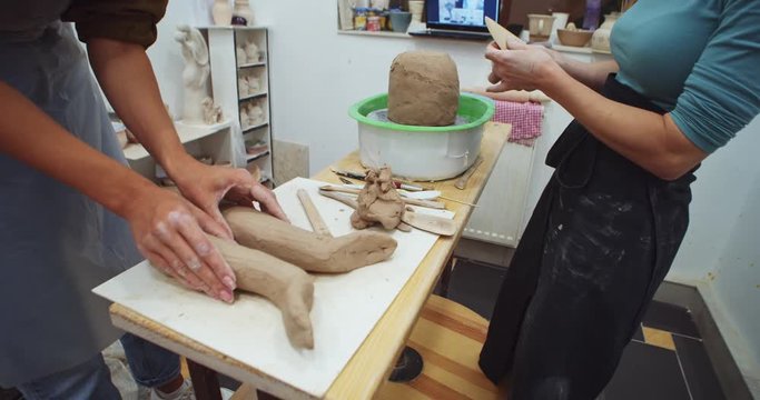 Closeup of young female sculptor hands creating clay ceramic flowerpot in art home studio interior. Handcraft performance. Enjoying creative process. Online classroom for artistic experience.