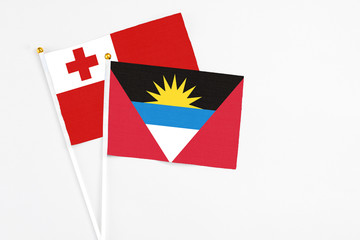 Obraz premium Antigua and Barbuda and Tonga stick flags on white background. High quality fabric, miniature national flag. Peaceful global concept.White floor for copy space.