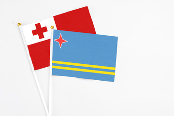 Aruba and Tonga stick flags on white background. High quality fabric, miniature national flag. Peaceful global concept.White floor for copy space.