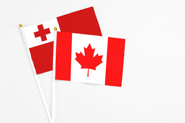 Canada and Tonga stick flags on white background. High quality fabric, miniature national flag. Peaceful global concept.White floor for copy space.