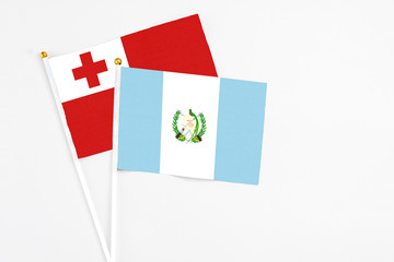 Guatemala and Tonga stick flags on white background. High quality fabric, miniature national flag. Peaceful global concept.White floor for copy space.