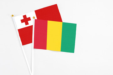 Guinea and Tonga stick flags on white background. High quality fabric, miniature national flag. Peaceful global concept.White floor for copy space.