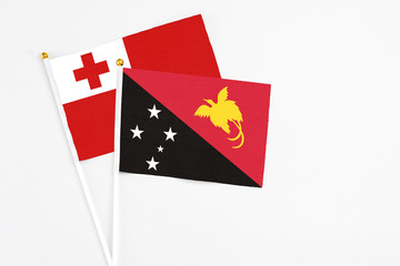 Papua New Guinea and Tonga stick flags on white background. High quality fabric, miniature national flag. Peaceful global concept.White floor for copy space.