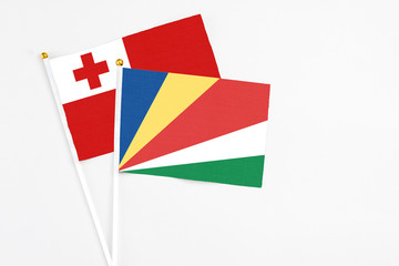 Seychelles and Tonga stick flags on white background. High quality fabric, miniature national flag. Peaceful global concept.White floor for copy space.