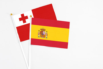 Spain and Tonga stick flags on white background. High quality fabric, miniature national flag. Peaceful global concept.White floor for copy space.