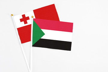 Sudan and Tonga stick flags on white background. High quality fabric, miniature national flag. Peaceful global concept.White floor for copy space.