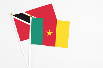 Naklejka premium Cameroon and Trinidad And Tobago stick flags on white background. High quality fabric, miniature national flag. Peaceful global concept.White floor for copy space.