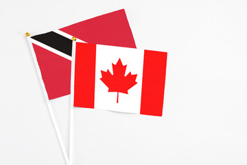 Canada and Trinidad And Tobago stick flags on white background. High quality fabric, miniature national flag. Peaceful global concept.White floor for copy space.