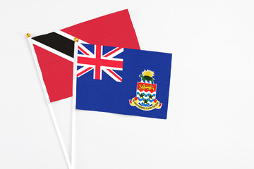Fototapeta premium Cayman Islands and Trinidad And Tobago stick flags on white background. High quality fabric, miniature national flag. Peaceful global concept.White floor for copy space.
