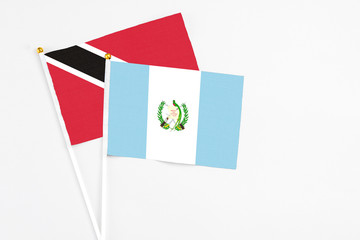 Guatemala and Trinidad And Tobago stick flags on white background. High quality fabric, miniature national flag. Peaceful global concept.White floor for copy space.