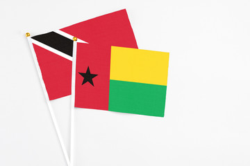 Guinea Bissau and Trinidad And Tobago stick flags on white background. High quality fabric, miniature national flag. Peaceful global concept.White floor for copy space.
