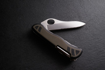 Multipurpose survivor tool knife on dark slate stone background