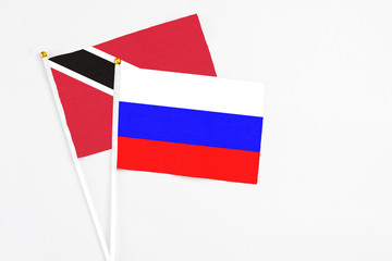 Russia and Trinidad And Tobago stick flags on white background. High quality fabric, miniature national flag. Peaceful global concept.White floor for copy space.