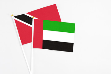 United Arab Emirates and Trinidad And Tobago stick flags on white background. High quality fabric, miniature national flag. Peaceful global concept.White floor for copy space.