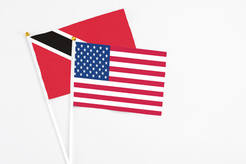 United States and Trinidad And Tobago stick flags on white background. High quality fabric, miniature national flag. Peaceful global concept.White floor for copy space.