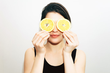 Headshot portrait of girl with oranges instead of eyes. White background. Young woman having fun.