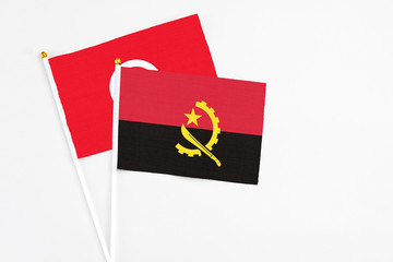 Angola and Tunisia stick flags on white background. High quality fabric, miniature national flag. Peaceful global concept.White floor for copy space.