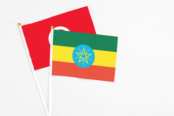 Ethiopia and Tunisia stick flags on white background. High quality fabric, miniature national flag. Peaceful global concept.White floor for copy space.