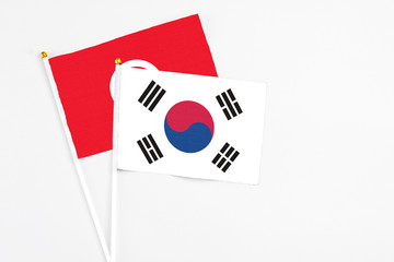 South Korea and Tunisia stick flags on white background. High quality fabric, miniature national flag. Peaceful global concept.White floor for copy space.