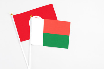 Madagascar and Tunisia stick flags on white background. High quality fabric, miniature national flag. Peaceful global concept.White floor for copy space.