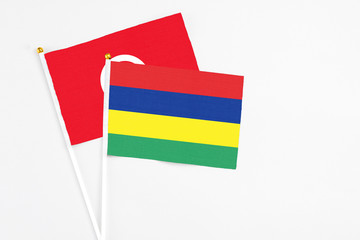Mauritius and Tunisia stick flags on white background. High quality fabric, miniature national flag. Peaceful global concept.White floor for copy space.