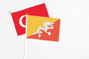 Bhutan and Turkey stick flags on white background. High quality fabric, miniature national flag. Peaceful global concept.White floor for copy space.