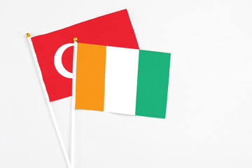 Fototapeta premium Cote D'Ivoire and Turkey stick flags on white background. High quality fabric, miniature national flag. Peaceful global concept.White floor for copy space.