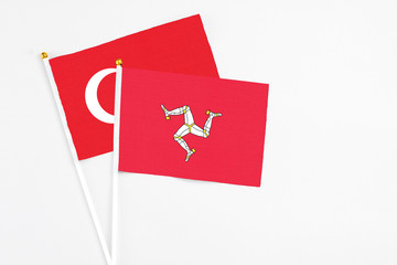 Isle Of Man and Turkey stick flags on white background. High quality fabric, miniature national flag. Peaceful global concept.White floor for copy space.