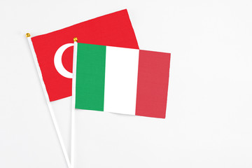 Italy and Turkey stick flags on white background. High quality fabric, miniature national flag. Peaceful global concept.White floor for copy space.