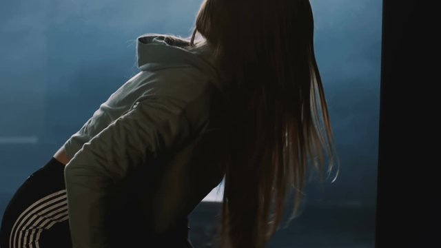 Silhouette of young athlete woman angry and furious alone in dark gym locker room, stressed under pressure slow motion.