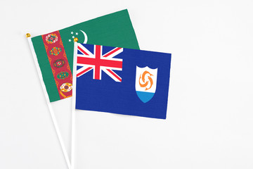 Fototapeta premium Anguilla and Turkmenistan stick flags on white background. High quality fabric, miniature national flag. Peaceful global concept.White floor for copy space.