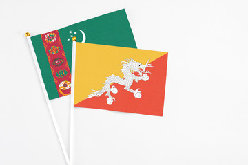 Bhutan and Turkmenistan stick flags on white background. High quality fabric, miniature national flag. Peaceful global concept.White floor for copy space.