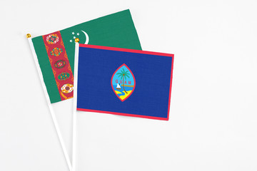 Guam and Turkmenistan stick flags on white background. High quality fabric, miniature national flag. Peaceful global concept.White floor for copy space.