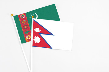 Fototapeta premium Nepal and Turkmenistan stick flags on white background. High quality fabric, miniature national flag. Peaceful global concept.White floor for copy space.