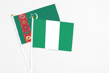 Nigeria and Turkmenistan stick flags on white background. High quality fabric, miniature national flag. Peaceful global concept.White floor for copy space.