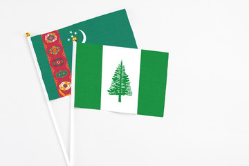 Norfolk Island and Turkmenistan stick flags on white background. High quality fabric, miniature national flag. Peaceful global concept.White floor for copy space.