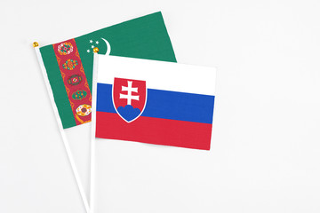 Slovakia and Turkmenistan stick flags on white background. High quality fabric, miniature national flag. Peaceful global concept.White floor for copy space.