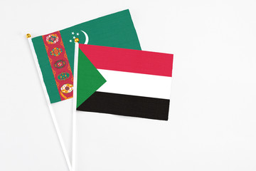 Sudan and Turkmenistan stick flags on white background. High quality fabric, miniature national flag. Peaceful global concept.White floor for copy space.