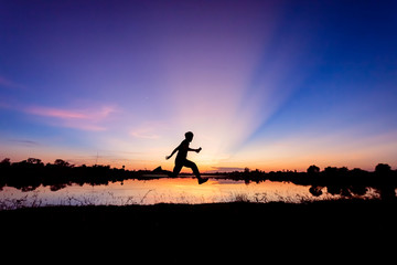 Freedom-young man is jumping at lake with sunset sky