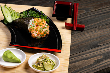 Salmon temaki sushi on black plate in black background. Japanese cuisine.