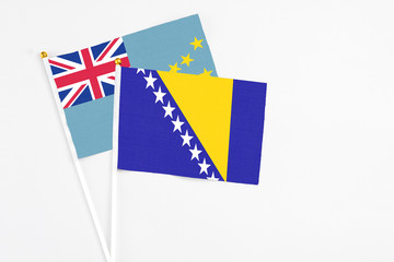 Bosnia Herzegovina and Tuvalu stick flags on white background. High quality fabric, miniature national flag. Peaceful global concept.White floor for copy space.