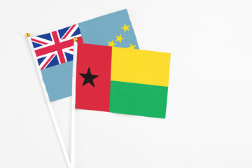 Guinea Bissau and Tuvalu stick flags on white background. High quality fabric, miniature national flag. Peaceful global concept.White floor for copy space.