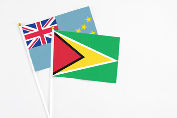 Guyana and Tuvalu stick flags on white background. High quality fabric, miniature national flag. Peaceful global concept.White floor for copy space.
