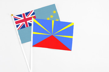 Reunion and Tuvalu stick flags on white background. High quality fabric, miniature national flag. Peaceful global concept.White floor for copy space.